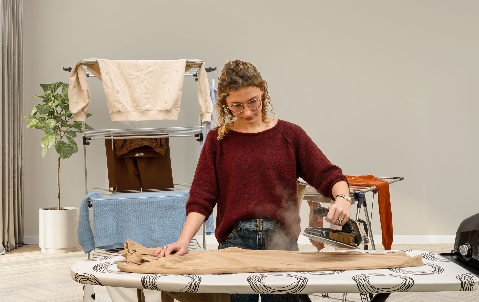 Stevige en veilige strijkplank met in de achtergrond in droogtoren en droogrek op kledij aan op te hangen